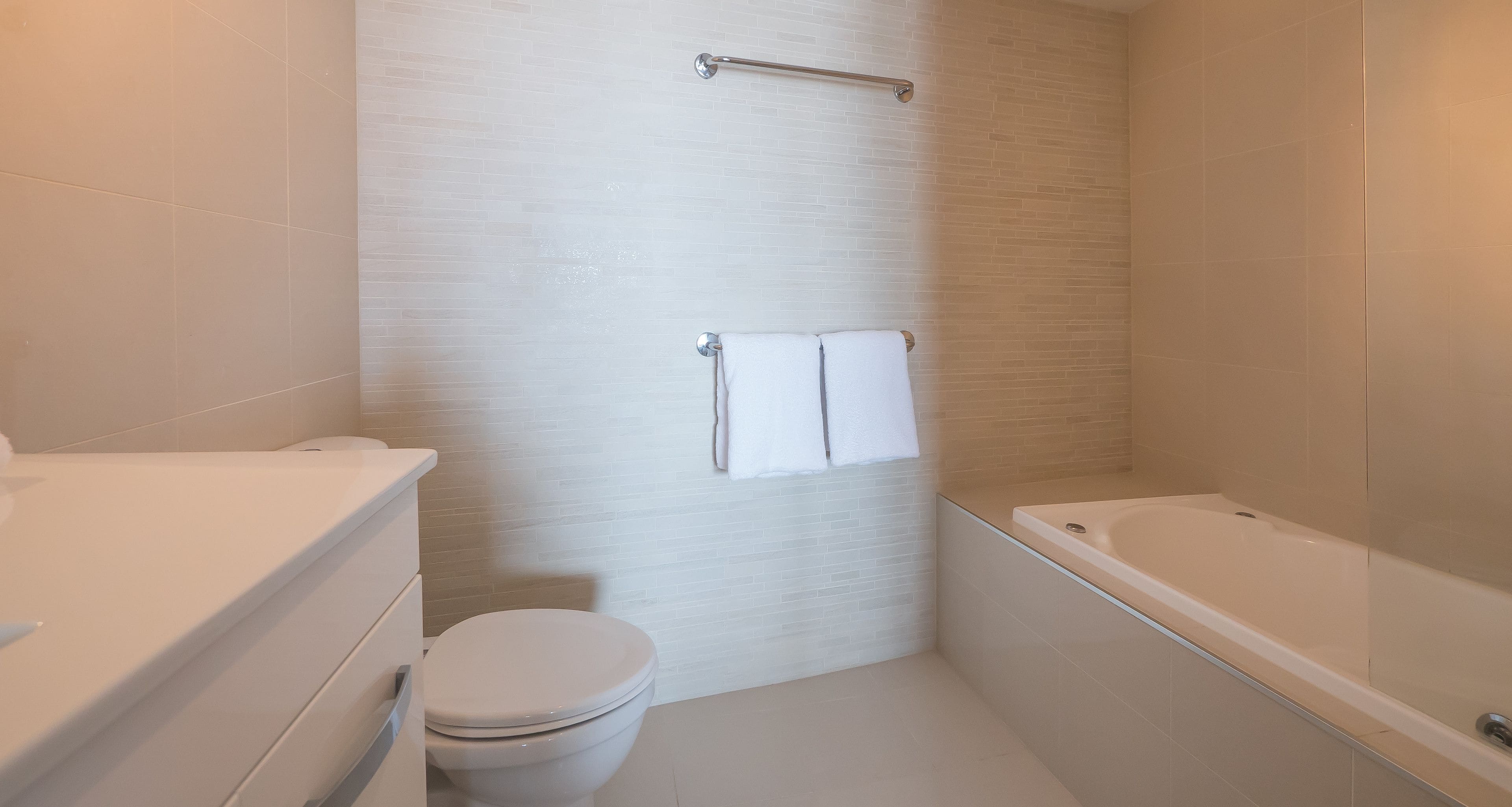 A modern bathroom with a toilet, a glass-enclosed bathtub, and a towel rack.