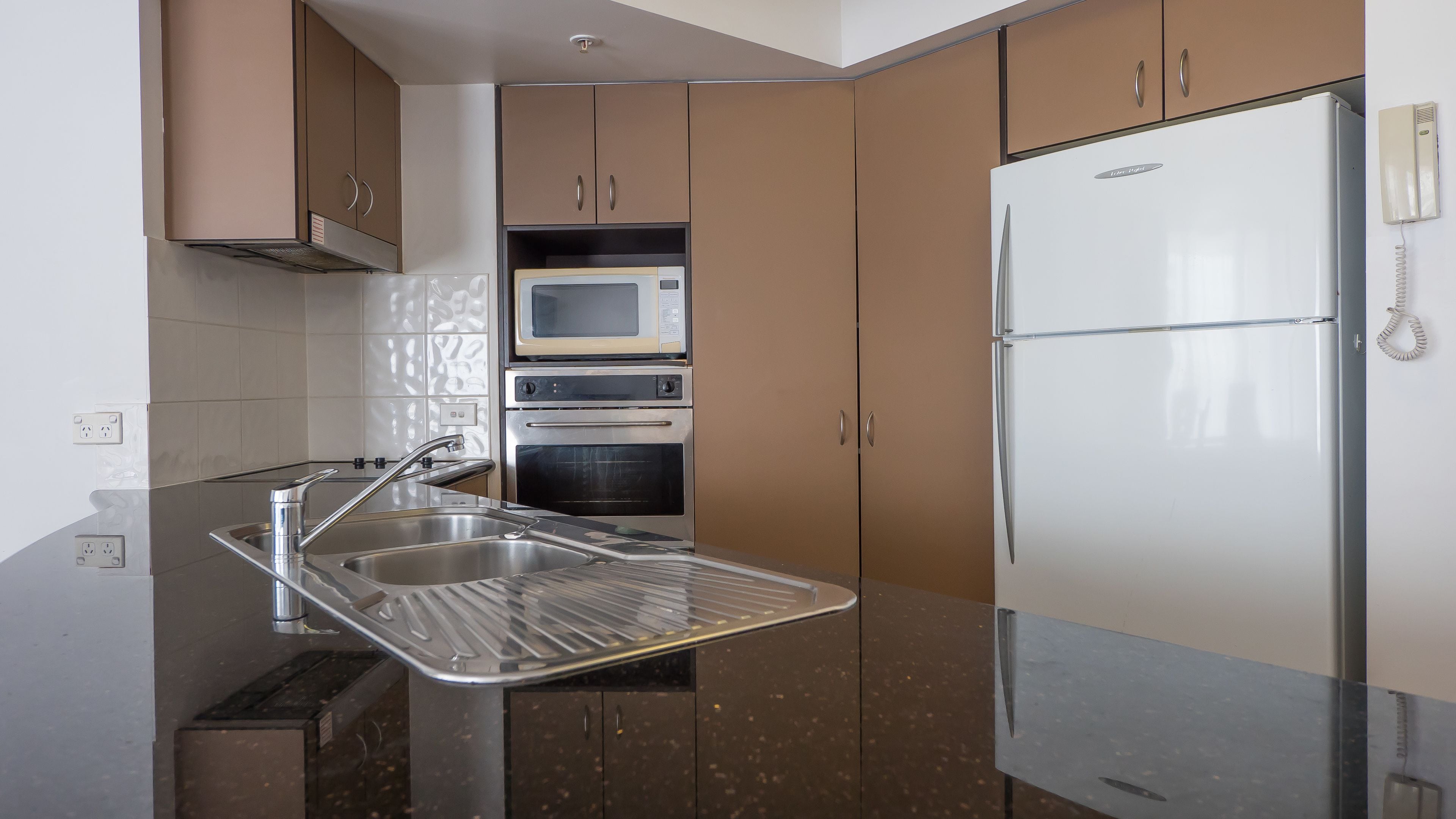 A modern kitchen with stainless steel appliances, a built-in oven, and a refrigerator.