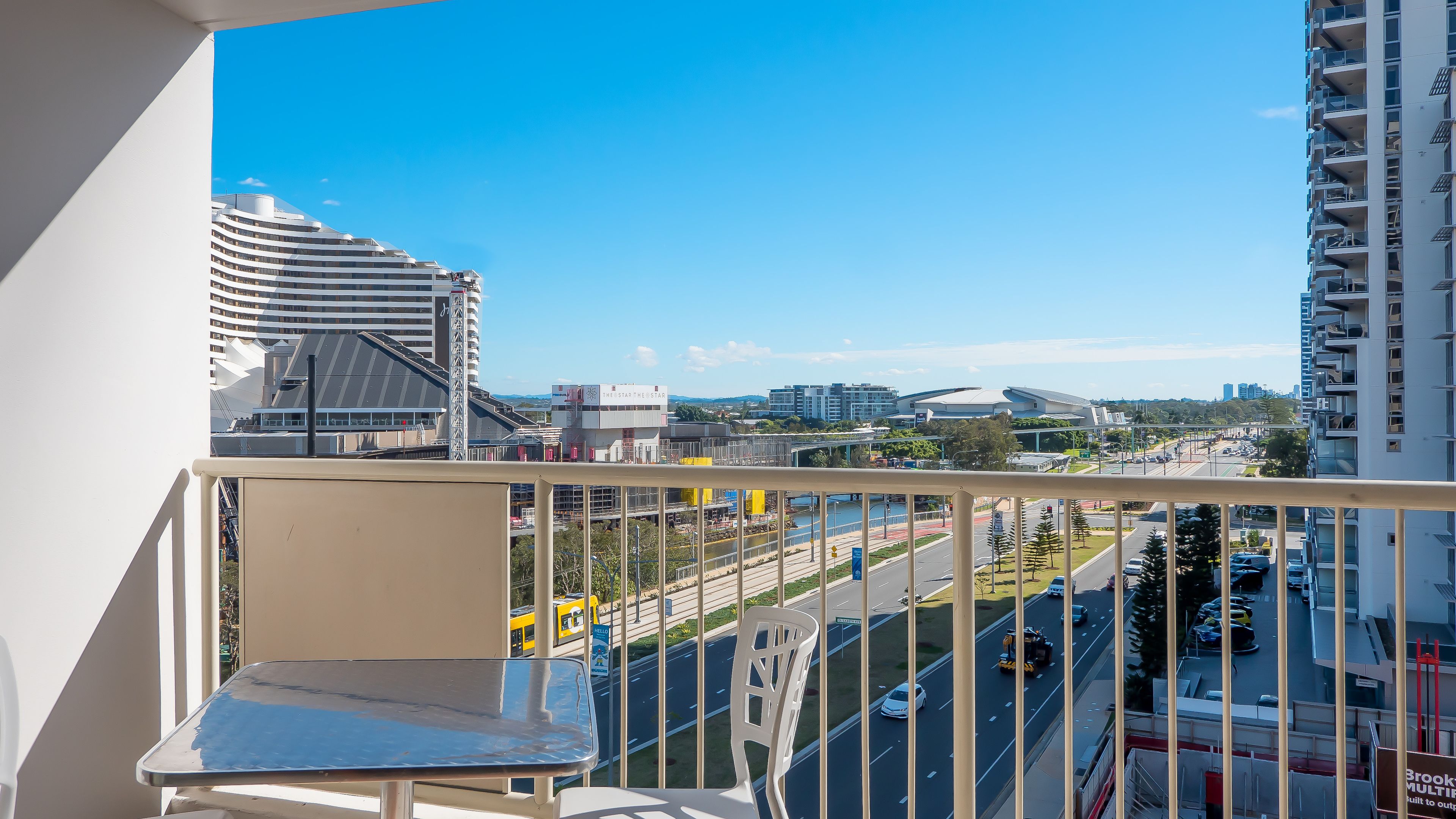 A balcony with a view of a modern cityscape, including a distinctive building with a curved roof and a tall skyscraper.