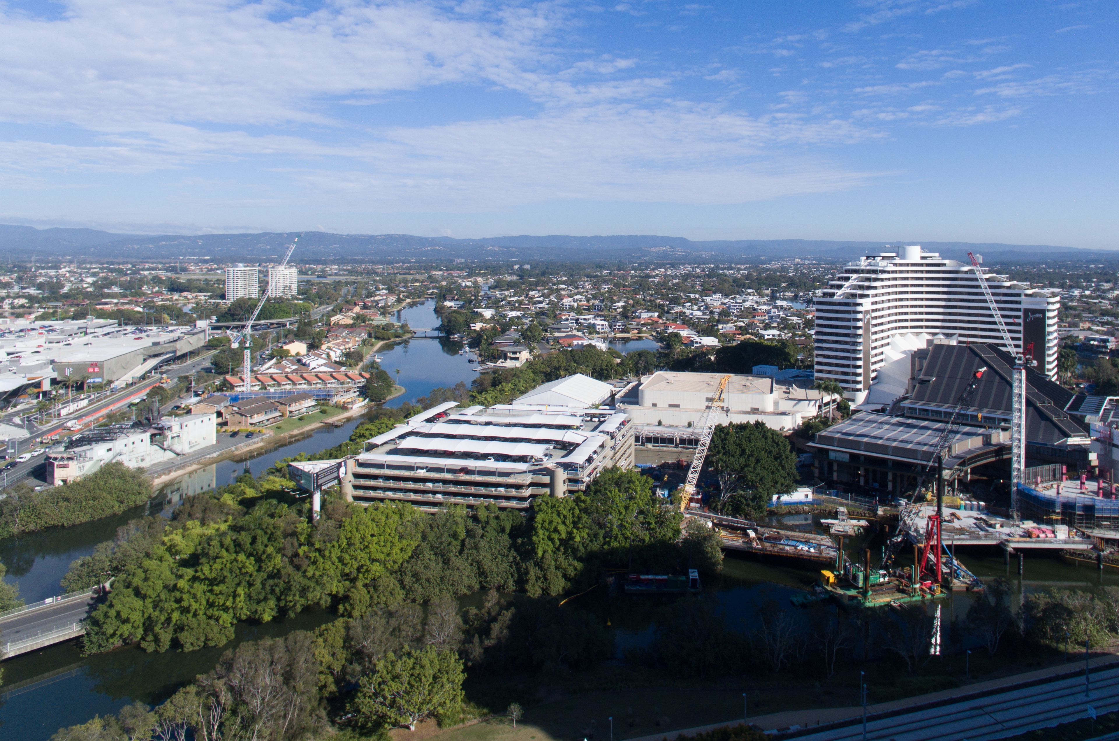 A cityscape with a large hotel featuring multiple floors and a distinctive curved roof, surrounded by a river and various buildings.