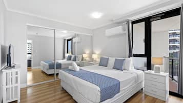 A modern hotel room with a large bed, a separate seating area, a flat-screen TV, and a balcony with a view.