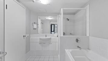Een moderne badkamer met douche, bad en wastafel.