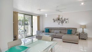 A modern living room with a glass dining table, a sofa, and a patterned side table. - BreakFree Diamond Beach (Mermaid Beach)