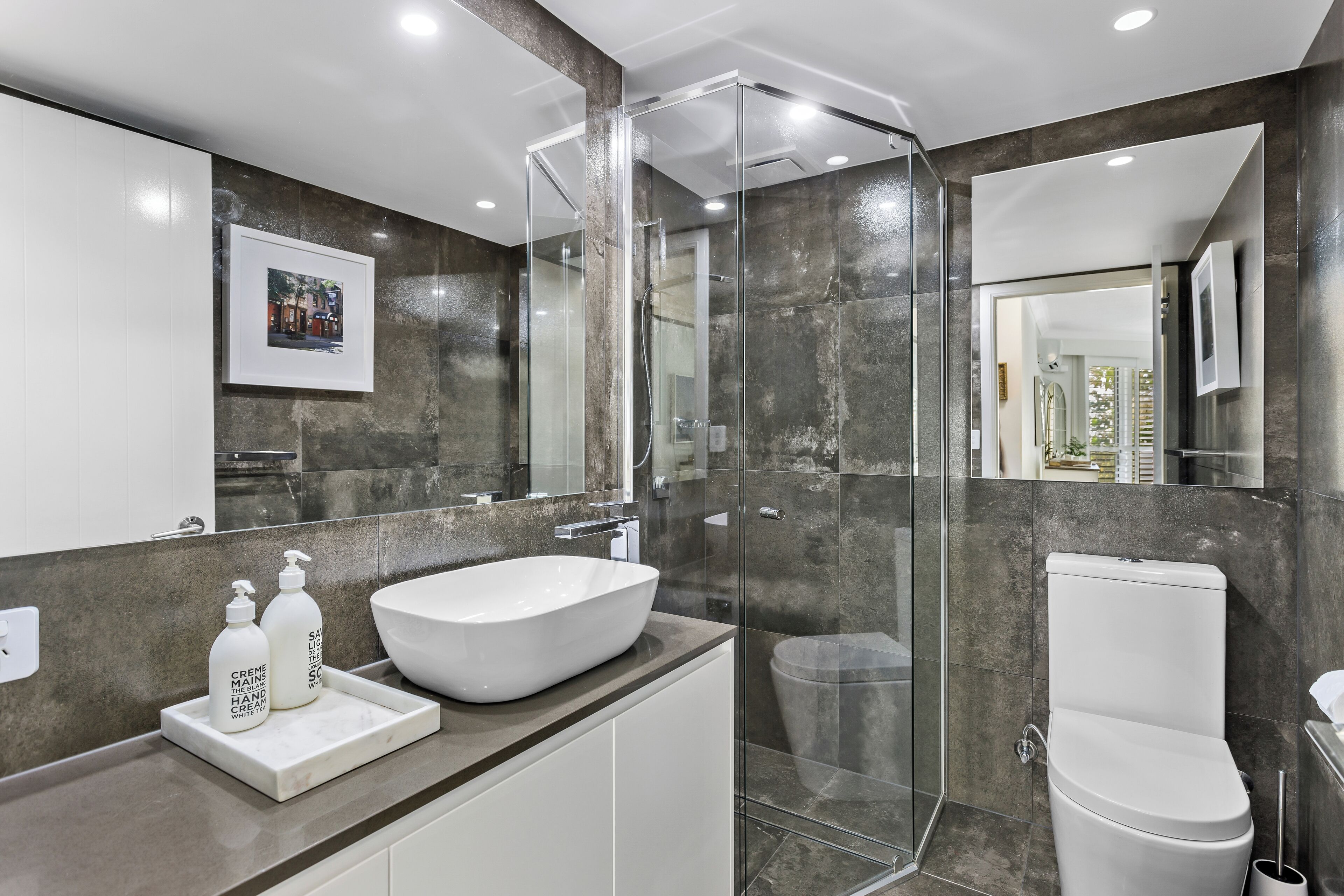 A modern bathroom with a glass-enclosed shower, a white sink, and a toilet.