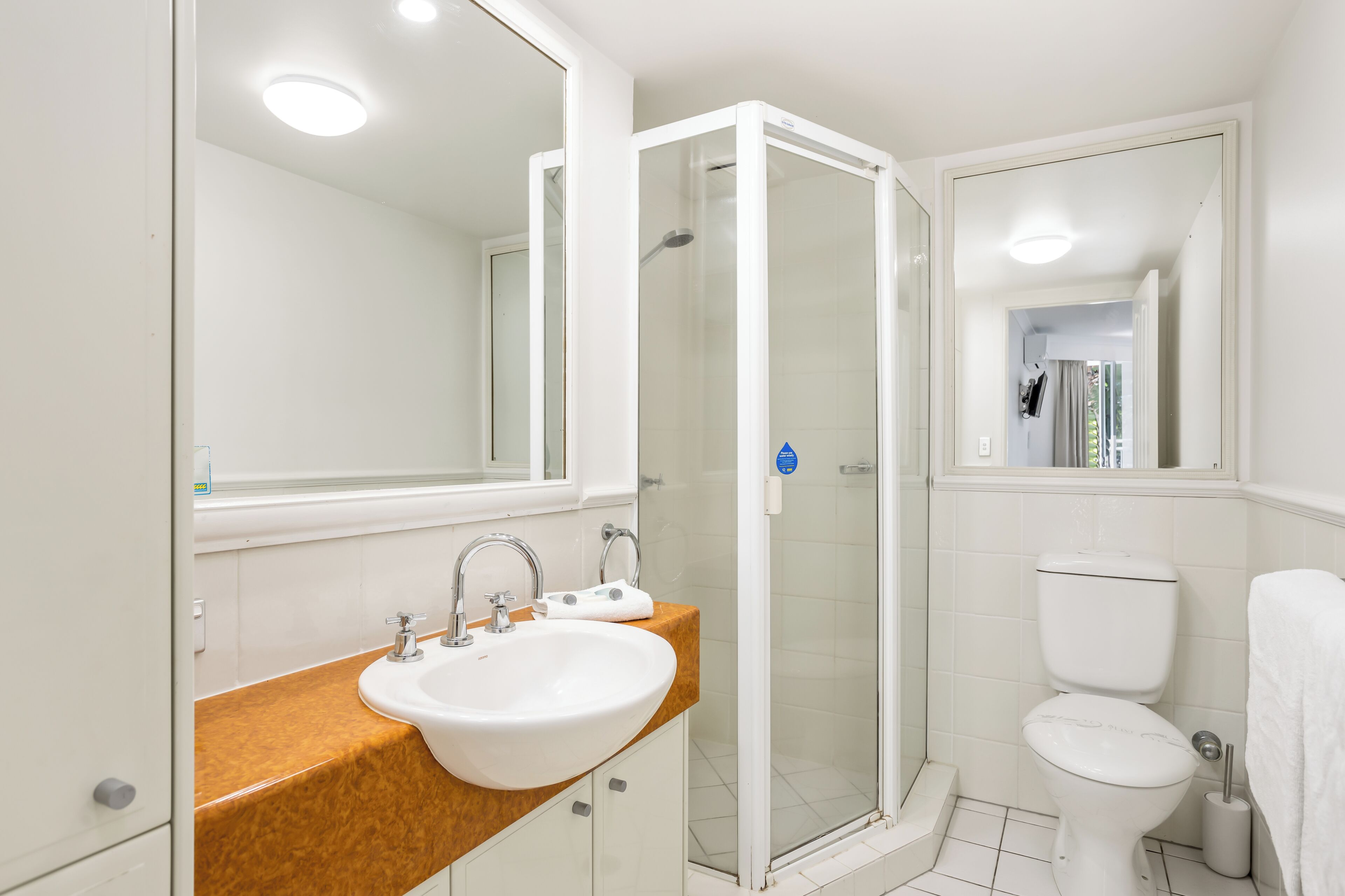 A bathroom with a white sink, a glass-enclosed shower, and a toilet.
