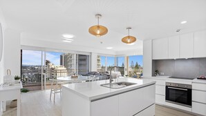 Una cocina moderna con una isla central, muebles blancos y un ventanal con vistas a la ciudad.