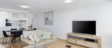 A modern living room with a sofa, coffee table, and TV stand.