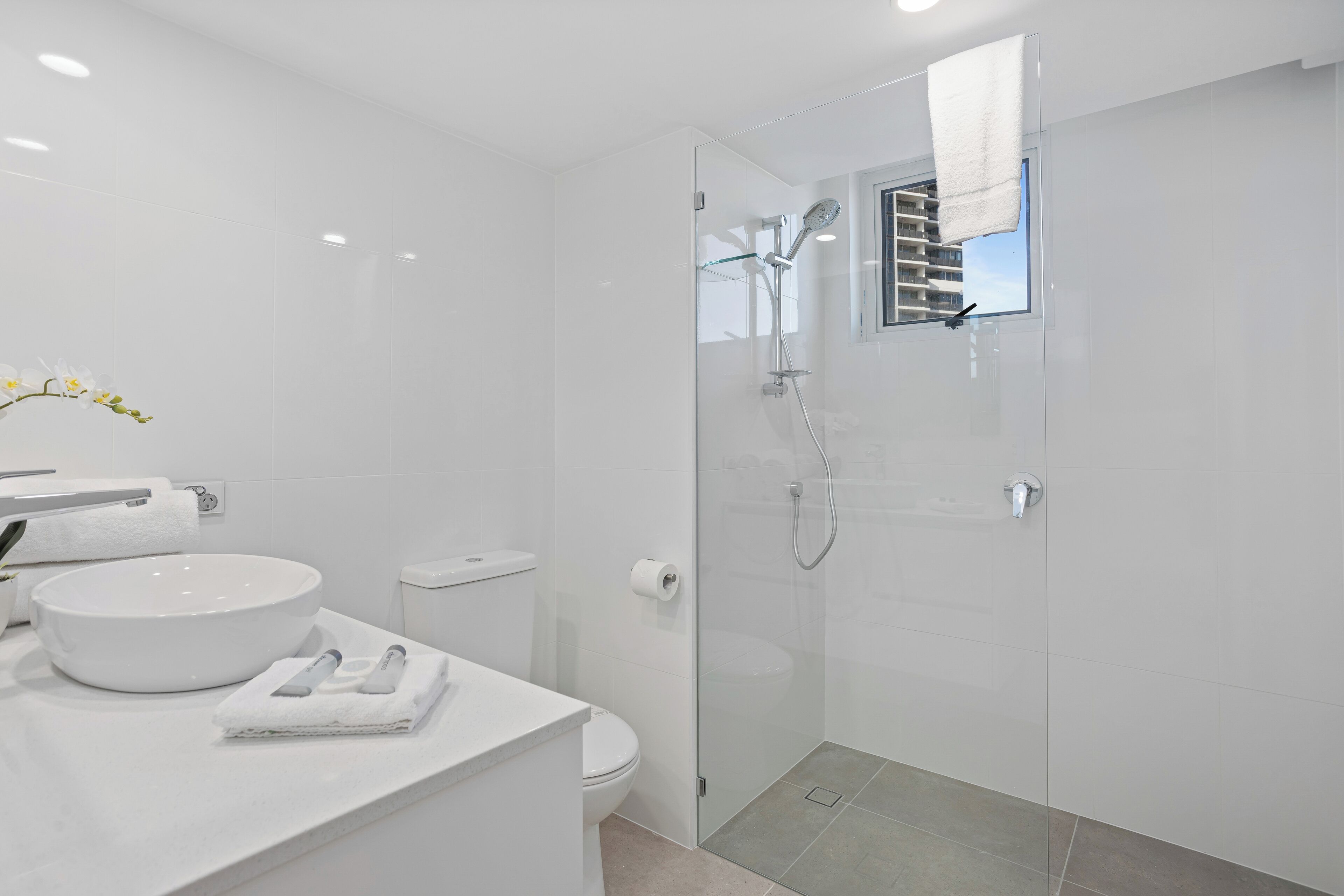 A modern bathroom with a glass-enclosed shower, a white sink, and a toilet.
