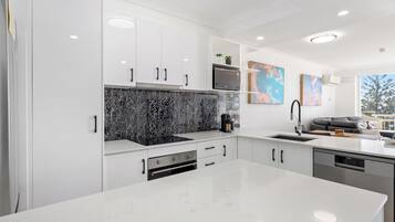 A modern kitchen with white cabinetry, a black marble backsplash, and a large island.