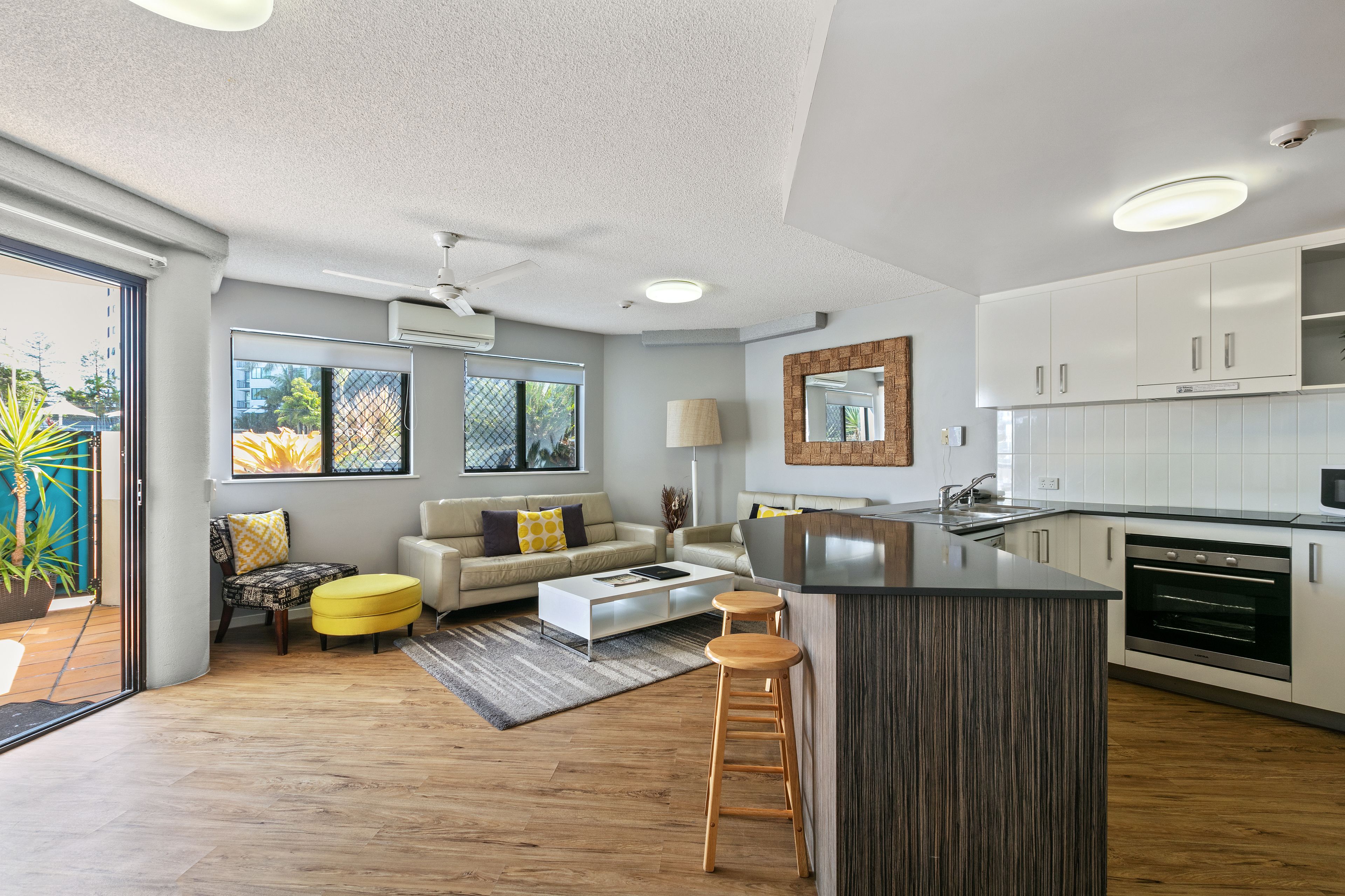 A modern kitchen with white cabinets, a central island, and a built-in oven.