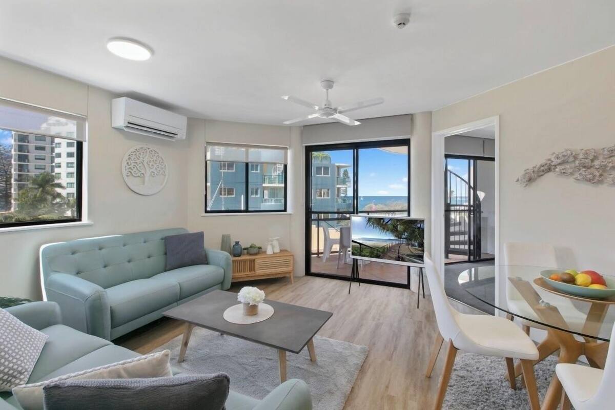 A modern living room with a sofa, coffee table, and dining area.