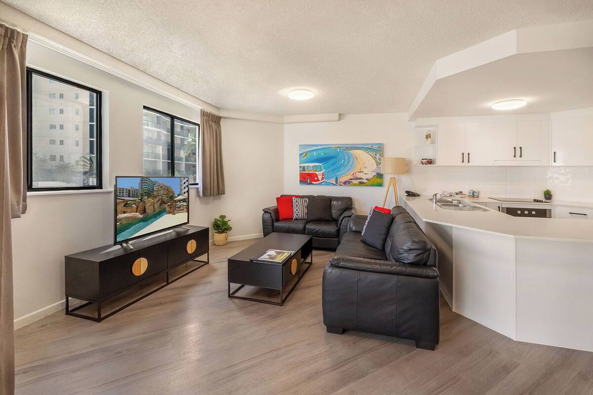 A modern living room with a sofa, coffee table, TV, and a painting.
