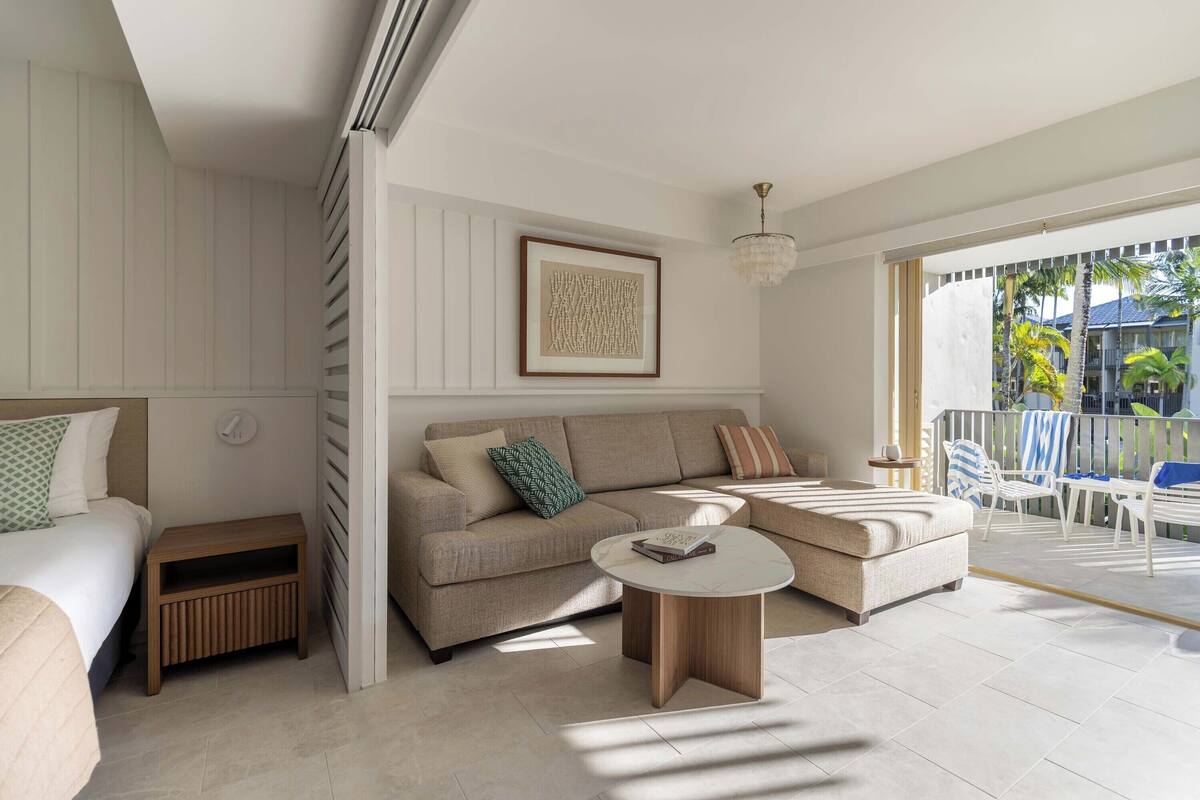 Een moderne woonkamer met een bank, een salontafel en een balkon met buitenmeubels.