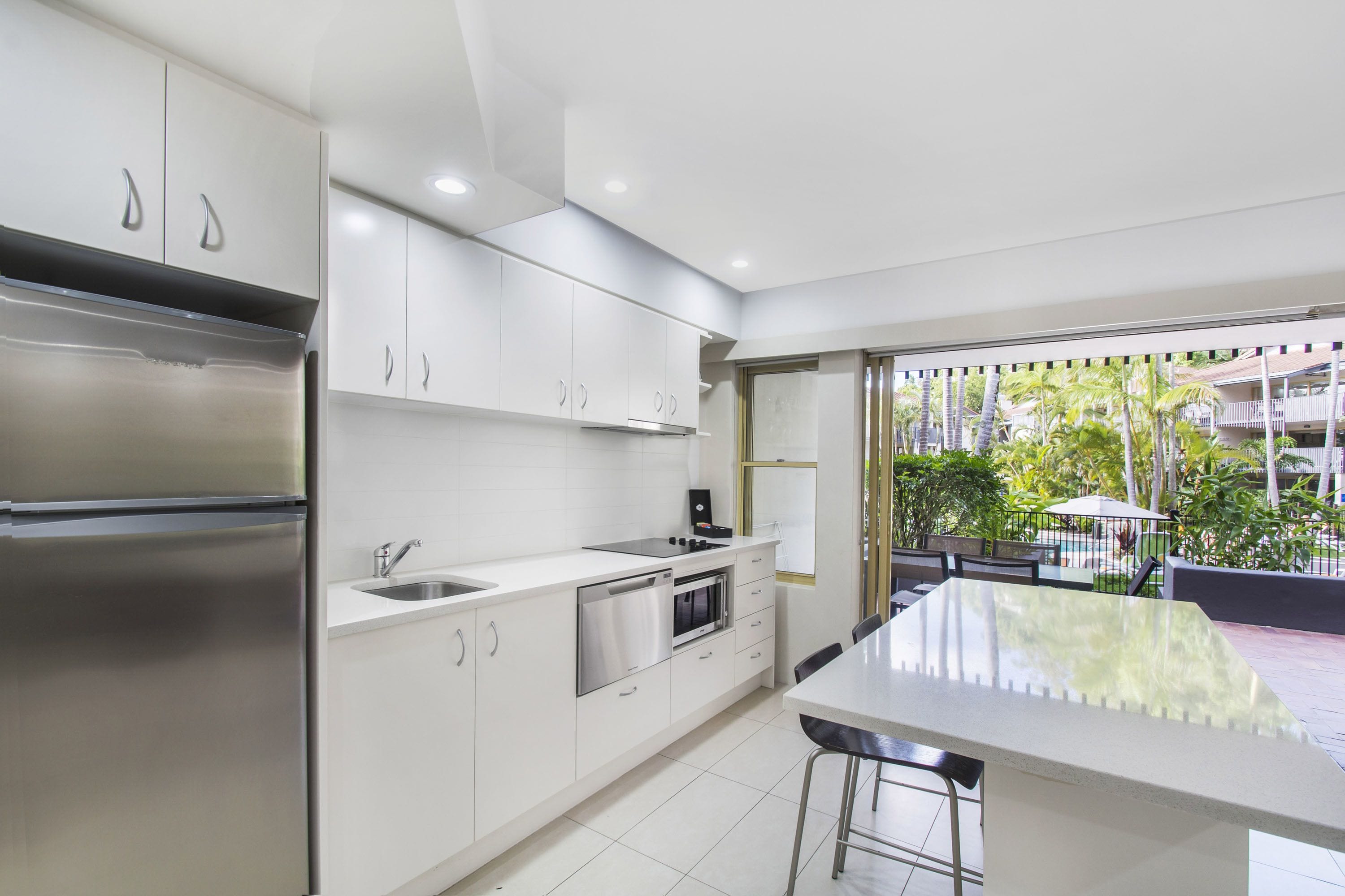 Una cocina moderna con electrodomésticos de acero inoxidable, armarios blancos y una isla grande con taburetes de bar.