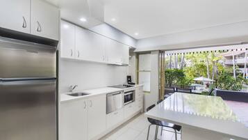 A modern kitchen with stainless steel appliances, white cabinetry, and a large island with bar stools.