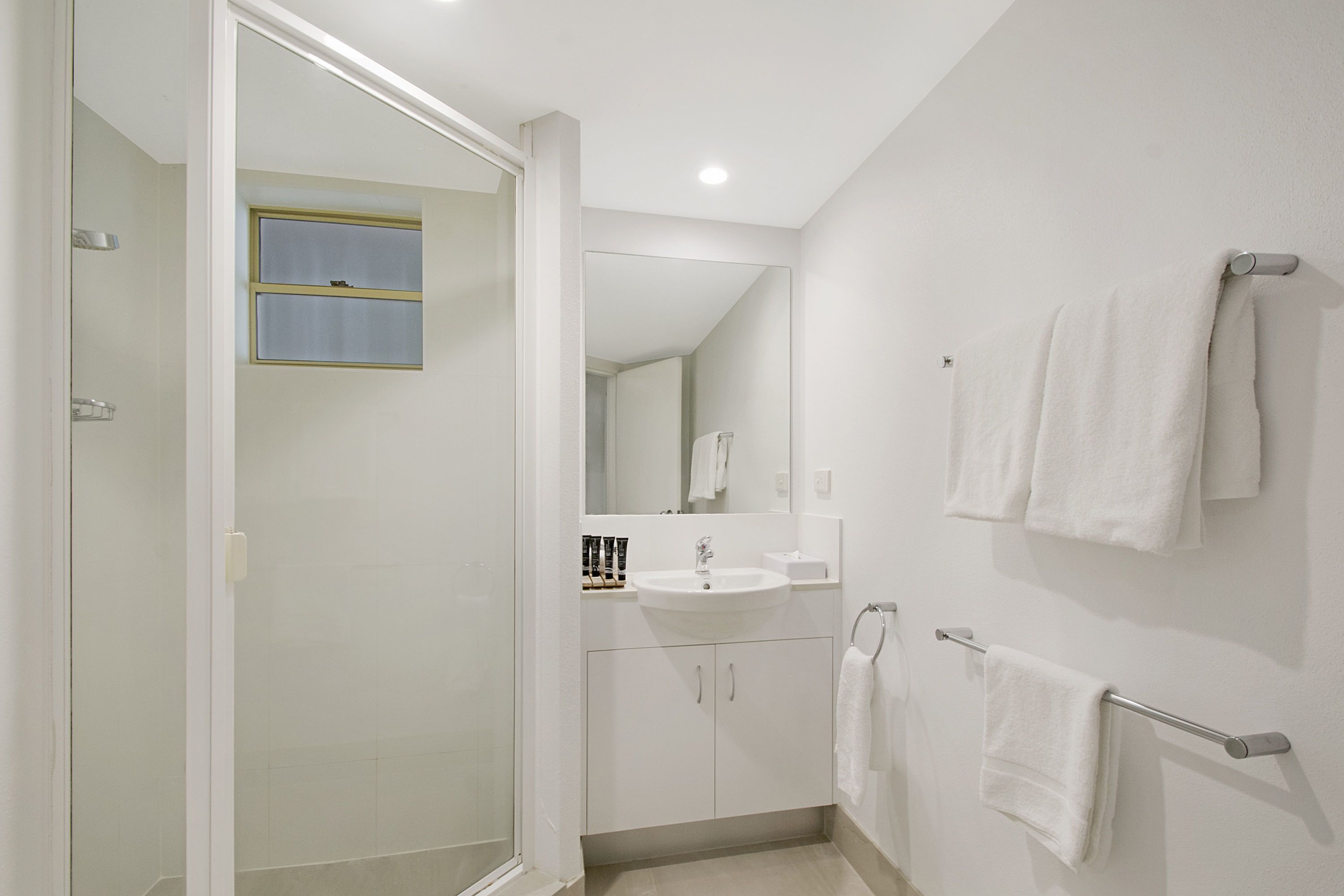 Une salle de bain moderne avec une douche à parois de verre, un lavabo et un miroir.