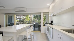 Eine moderne Küche mit weißen Arbeitsplatten, Edelstahlgeräten und einer Bar.