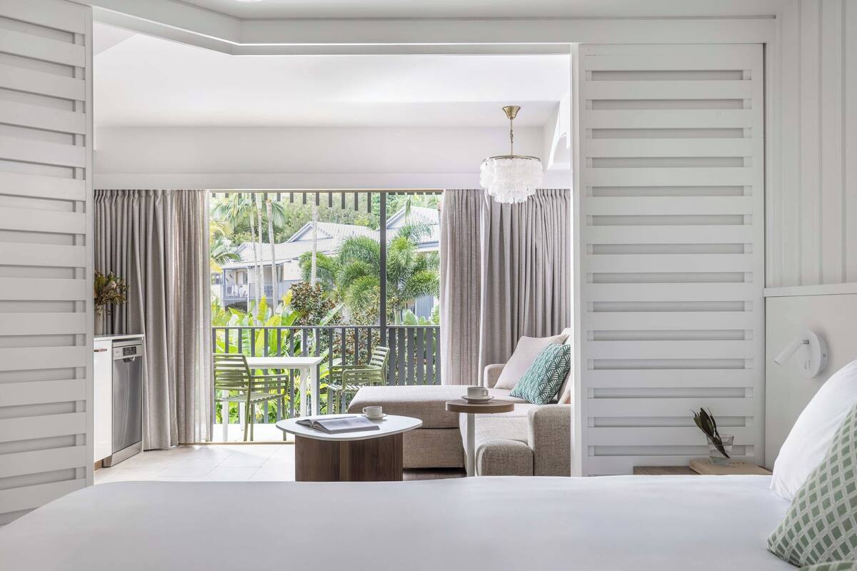 Een moderne hotelkamer met balkon, een bank, een bijzettafeltje en een bed.