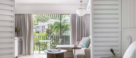 A modern hotel room with a balcony, a sofa, a coffee table, and a bed.