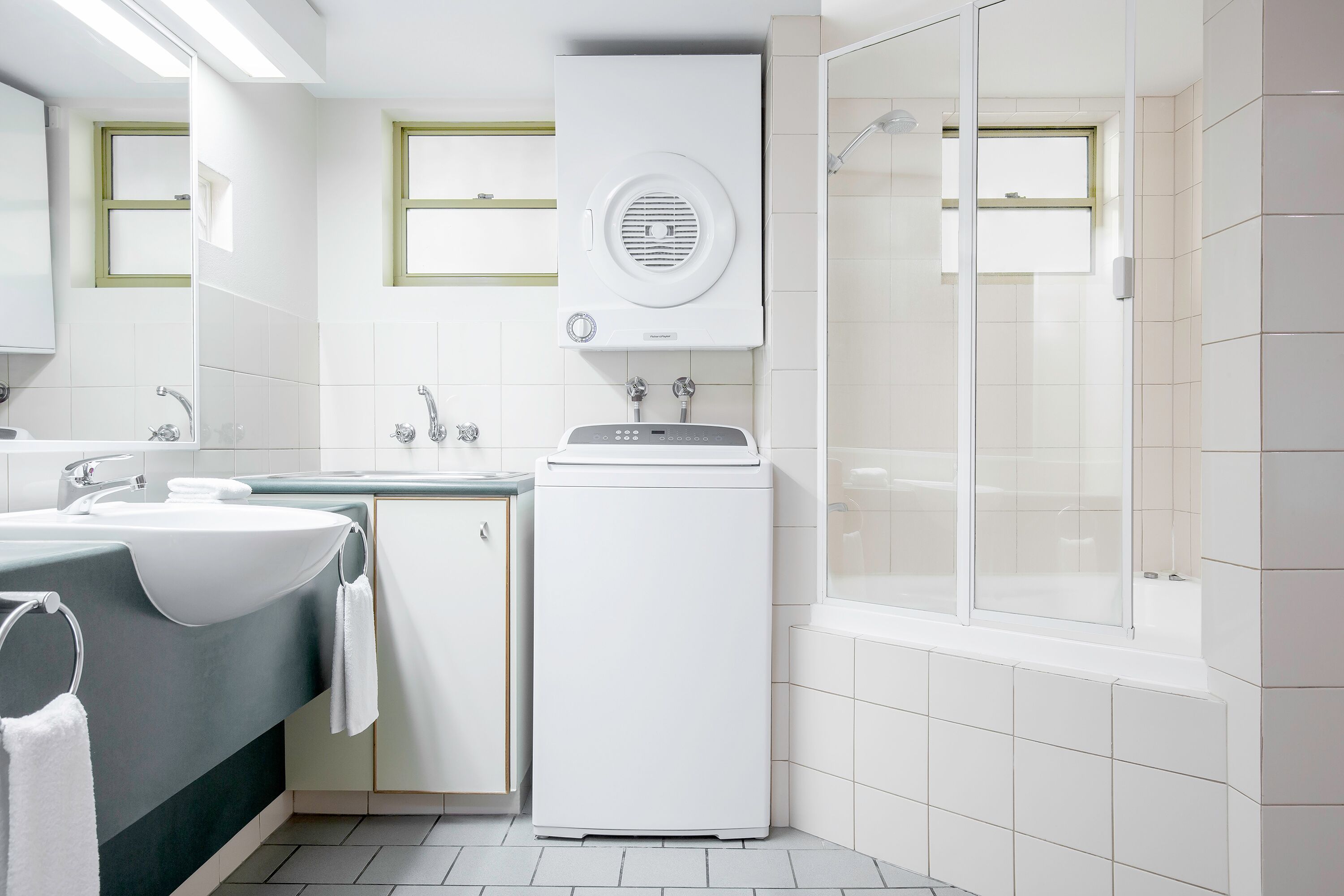 A modern bathroom with a large sink, a toilet, a shower, and a built-in dryer.