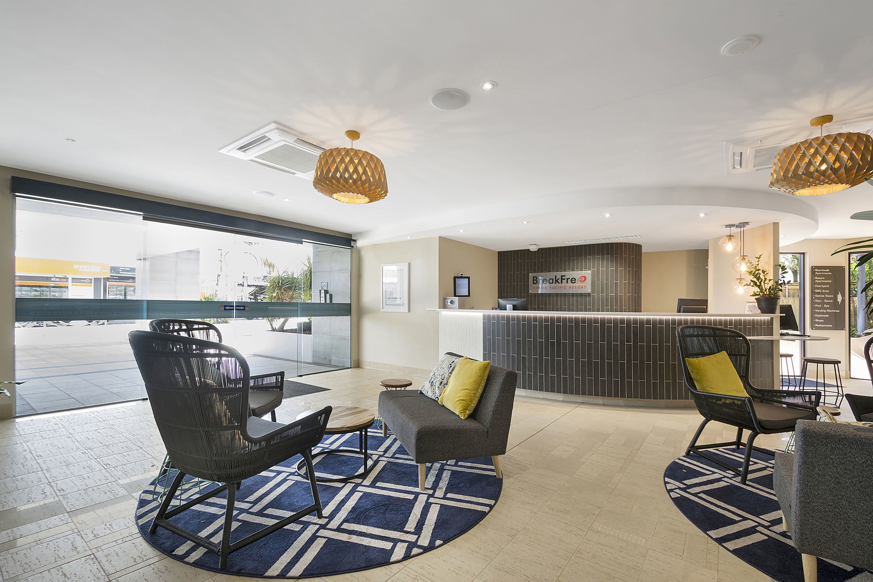 Eine moderne Hotelhalle mit einer Rezeption, einer Sitzecke und großen Fenstern.