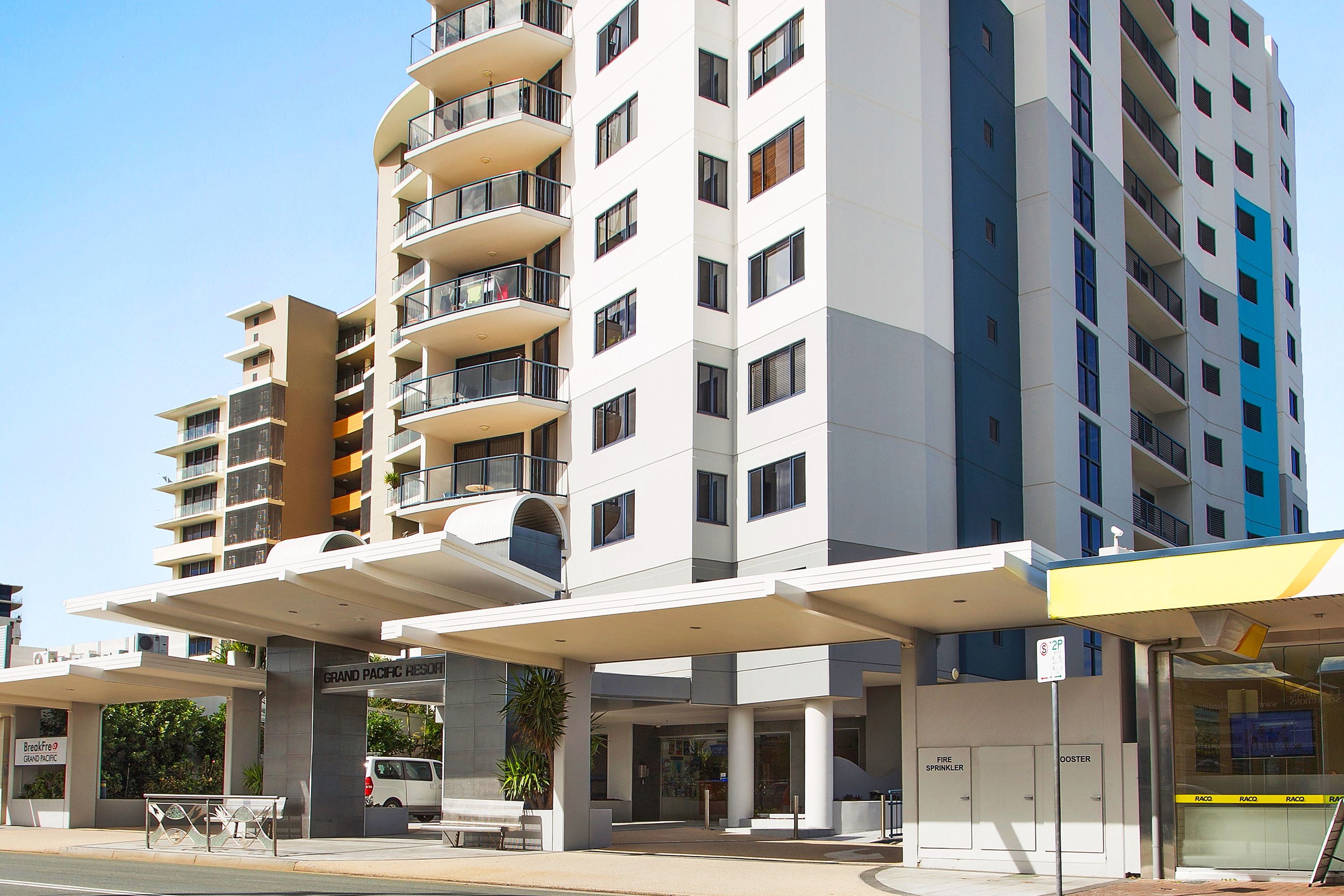 A multi-story hotel with balconies, a covered entrance, and a sign for 'Grand Pacific Resort'.