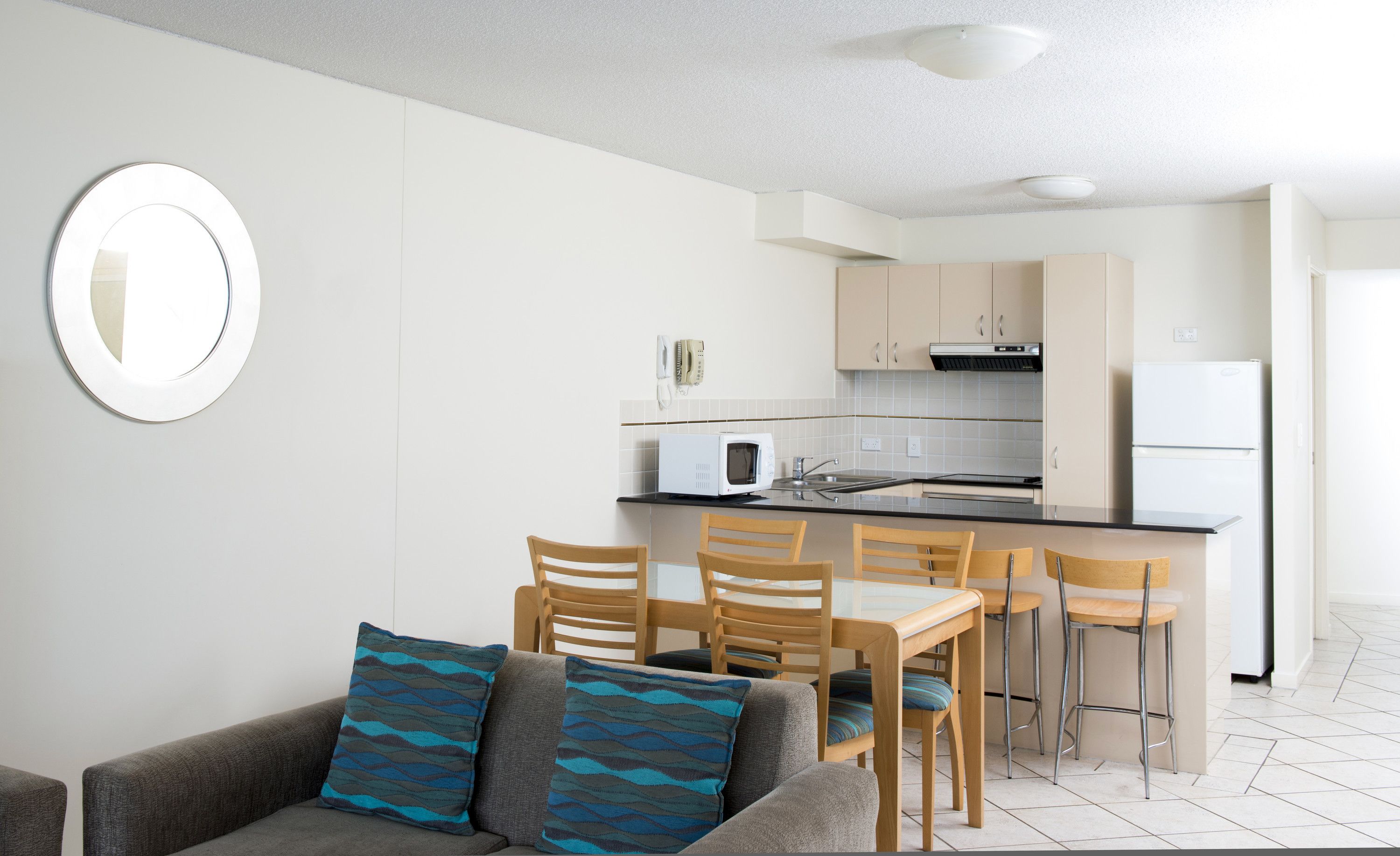 A compact kitchen with a microwave, stove, and refrigerator. There is a dining area with a table and chairs.