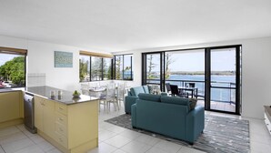 A modern kitchen with a dining area, a sofa, and a view of the sea. - BreakFree Grand Pacific Resort (Caloundra)
