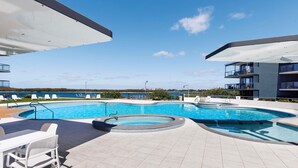 A swimming pool with a view of the sea, outdoor seating, and modern architecture. - BreakFree Grand Pacific Resort (Caloundra)