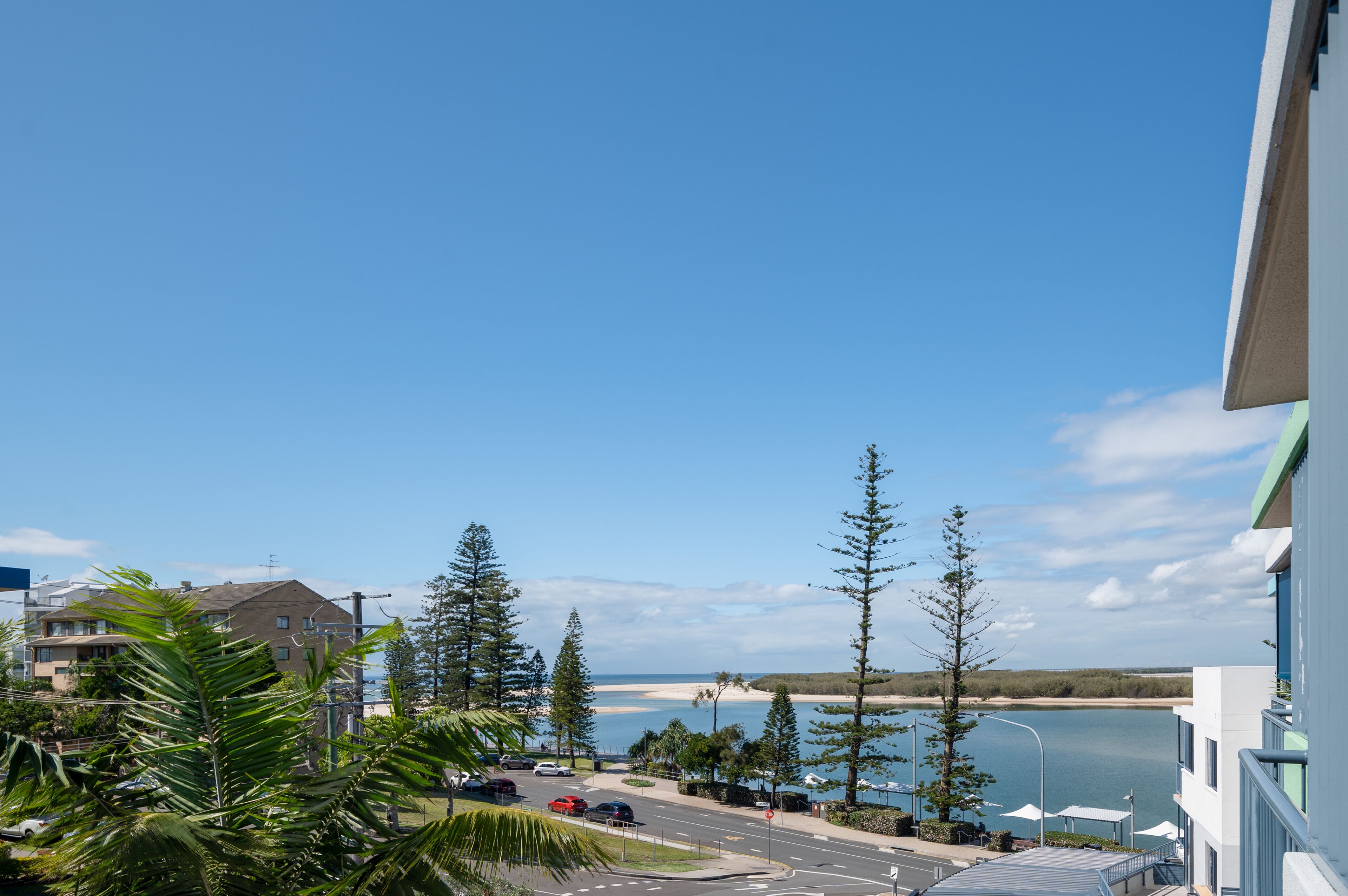 A coastal view with a road, trees, and a building.