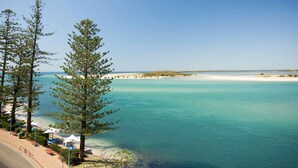A coastal view with clear turquoise waters, a sandy beach, and a few trees. - BreakFree Grand Pacific Resort (Caloundra)
