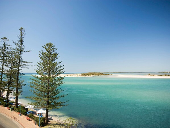 A coastal view with clear turquoise waters, a sandy beach, and a few trees. - BreakFree Grand Pacific Resort (Caloundra)