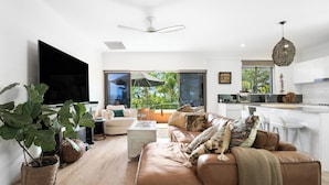 Uma sala de estar moderna com sofá, mesa de centro e uma planta grande.