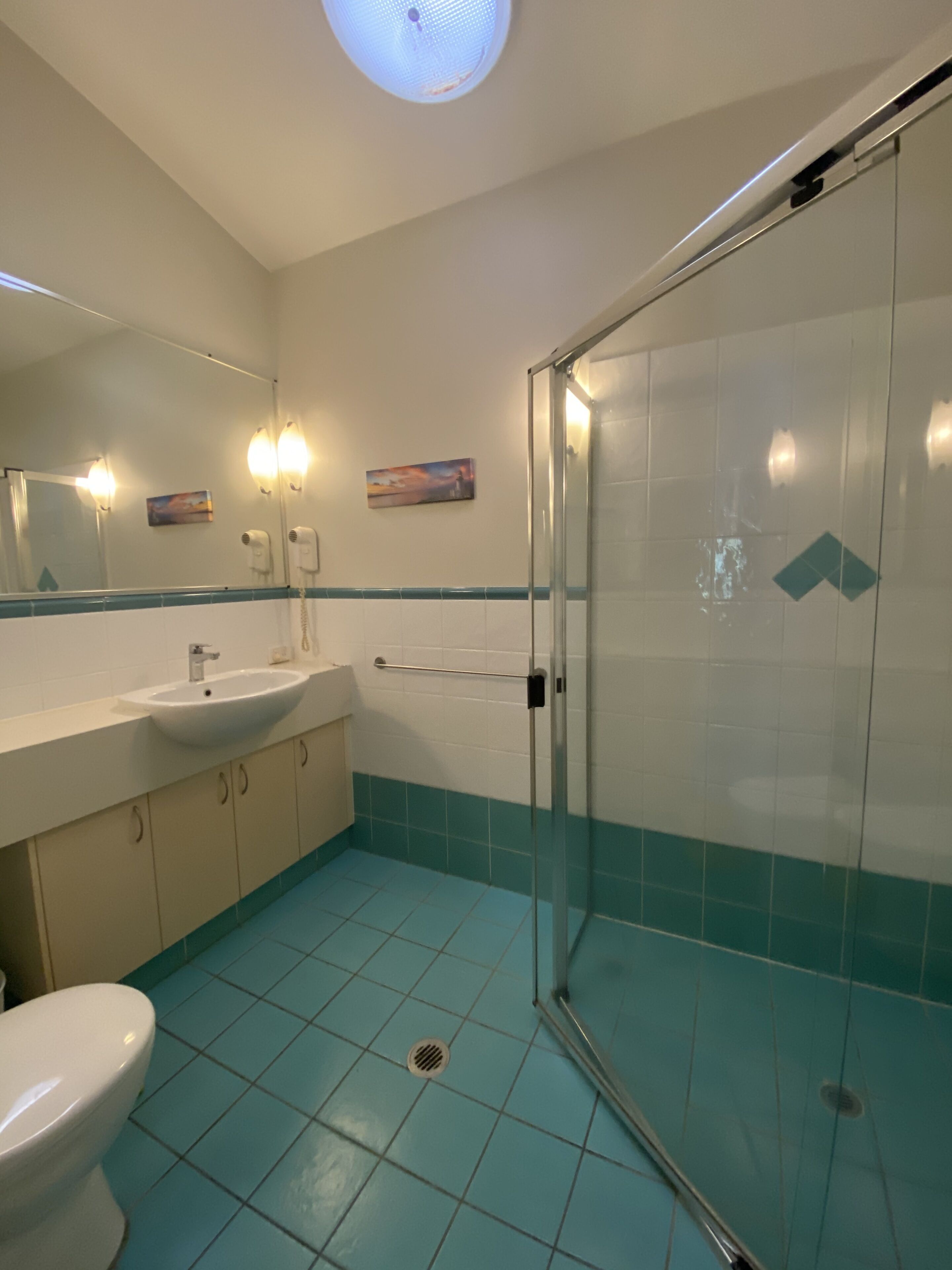 A bathroom with a glass shower enclosure, a sink, and a toilet.