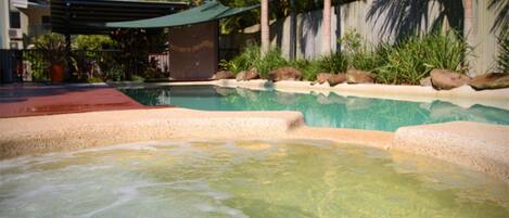 A swimming pool with clear water, surrounded by rocks and greenery.