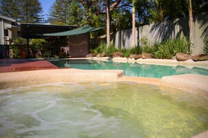 Una piscina con agua cristalina, rodeada de rocas y follaje.