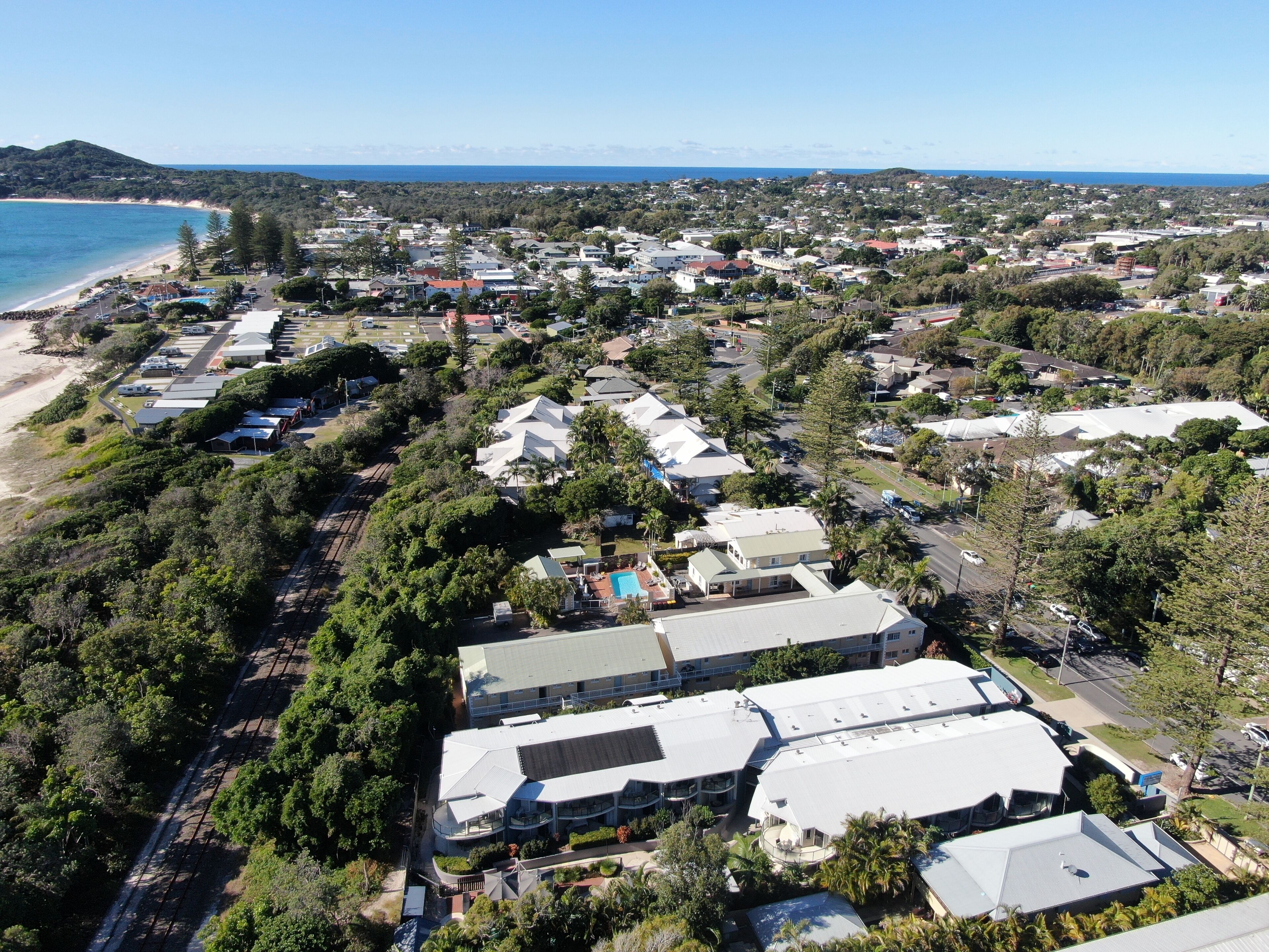 An aerial view of a coastal residential area with houses, a beach, and a road.
