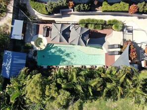 An aerial view of a residential property with a swimming pool, patio furniture, and lush greenery. - Byron Beachcomber (Byron Bay)