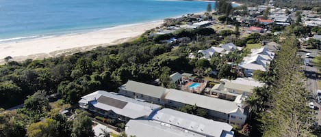 A coastal residential area with houses, a beach, and a hilly landscape in the background.