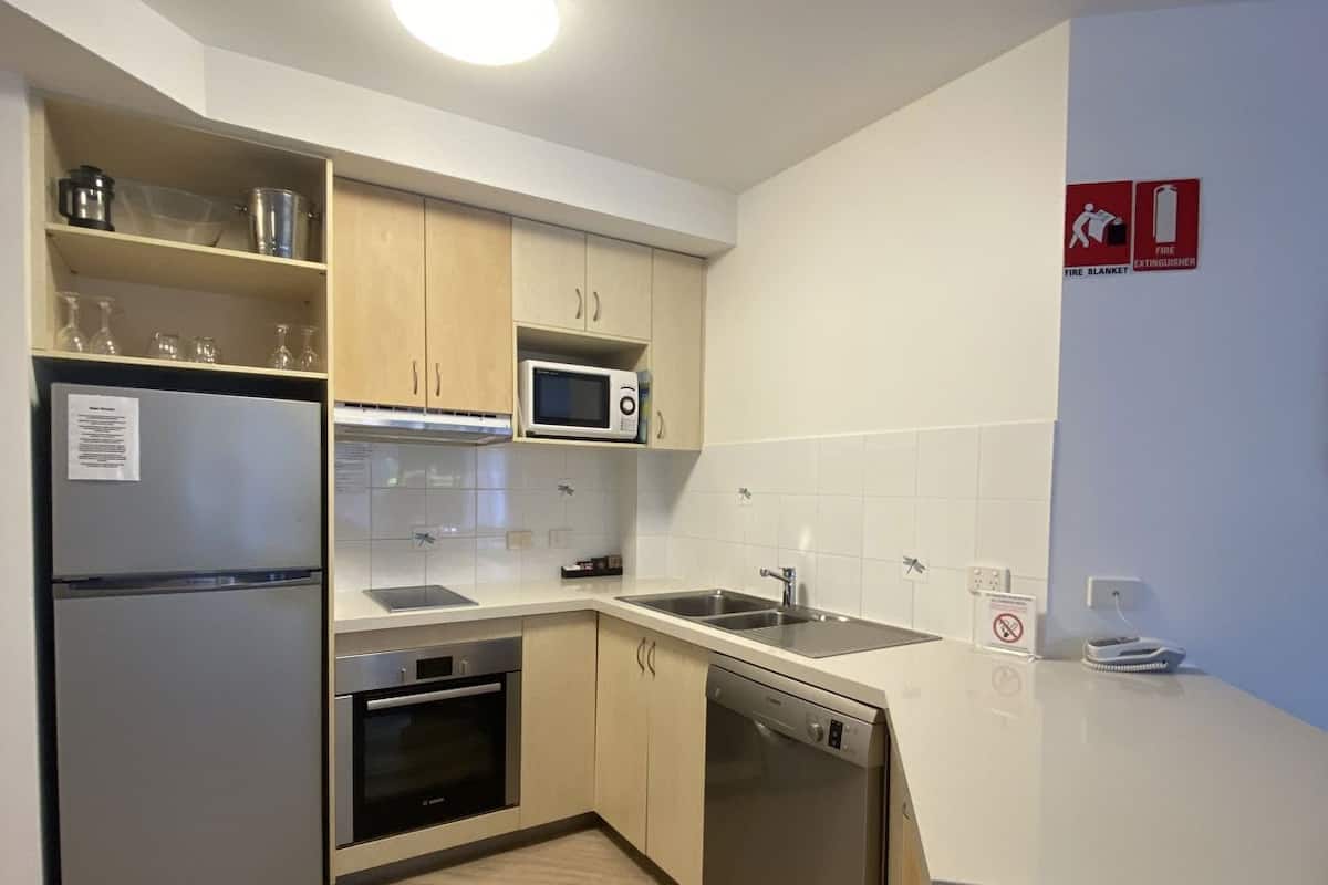 A modern kitchen with stainless steel appliances, wooden cabinets, and a white countertop.