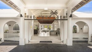 A covered entrance with a palm tree sign, a staircase, and a view of the building's interior. - Mantra PortSea (Port Douglas)