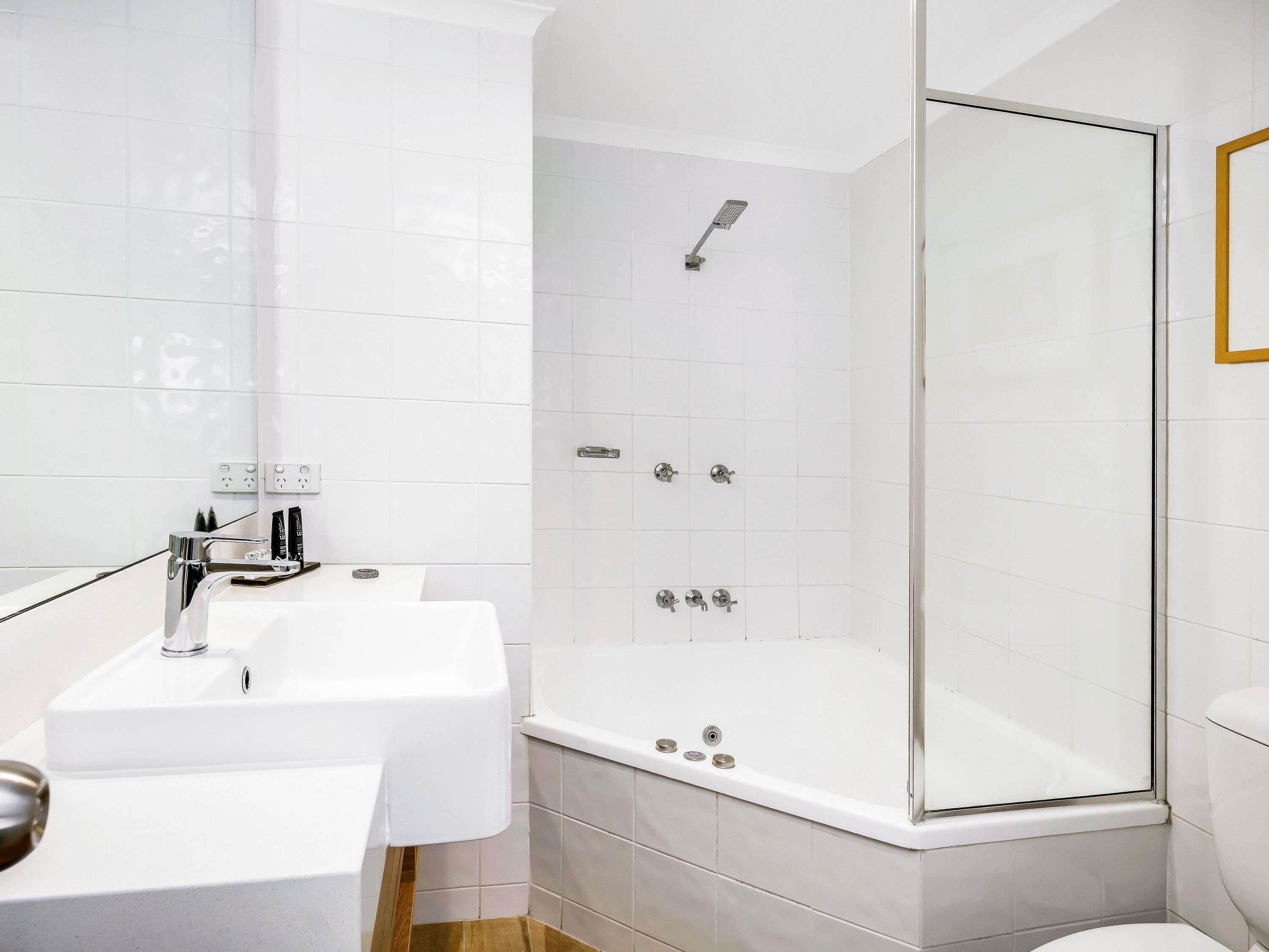 A modern bathroom with a shower, sink, and toilet.