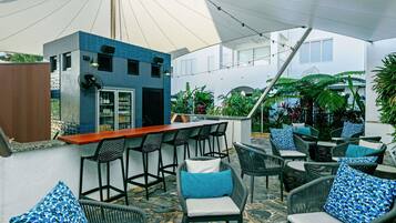 An outdoor bar area with seating, a refrigerator, and potted plants.