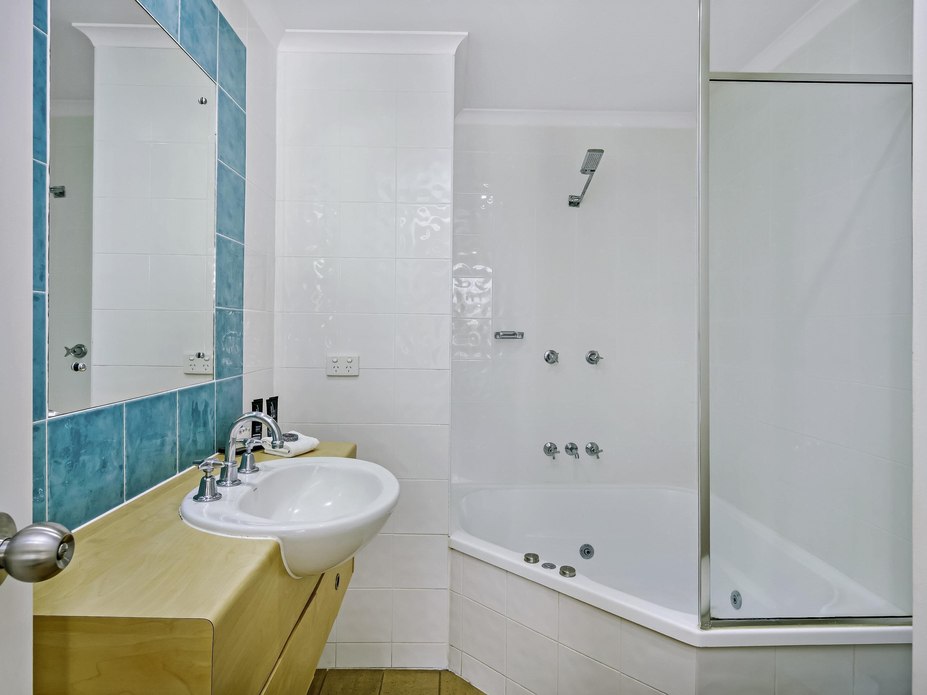 A bathroom with a sink, mirror, and shower.