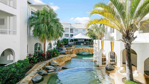 A resort with a pool, palm trees, and a bar. - Mantra PortSea (Port Douglas)
