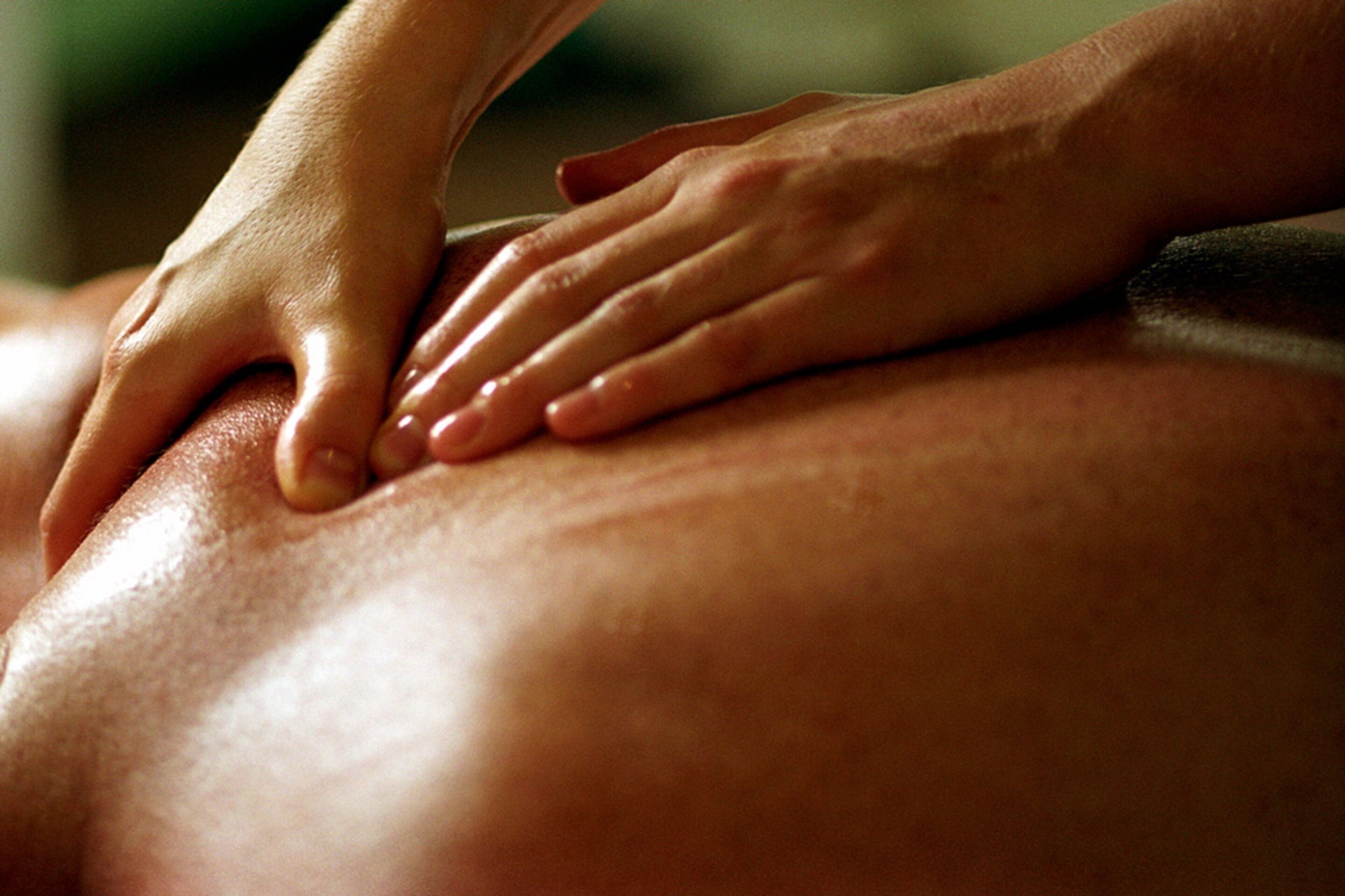 A close-up of hands performing a massage on a person's back.
