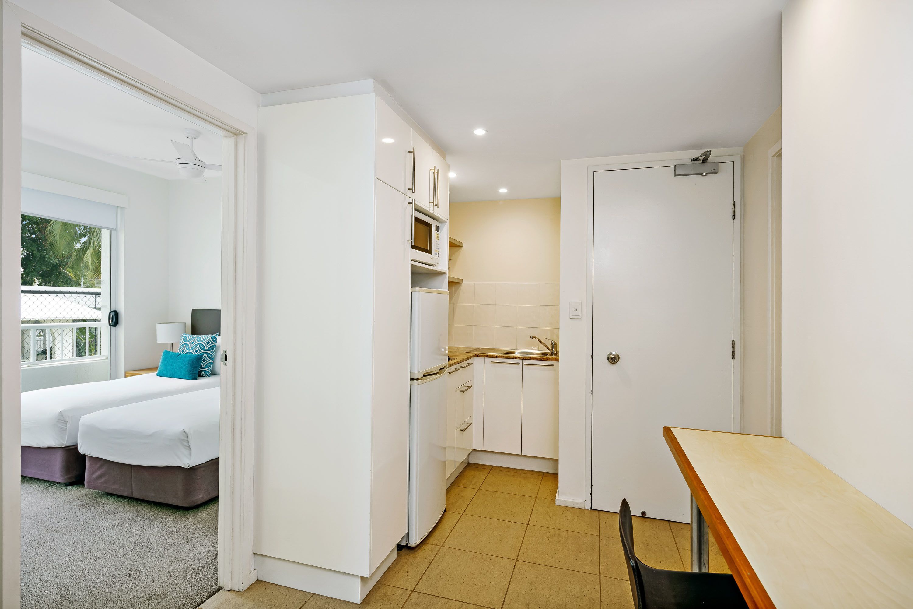 Una habitación de hotel compacta con kitchenette, cama con vistas y un pequeño comedor.