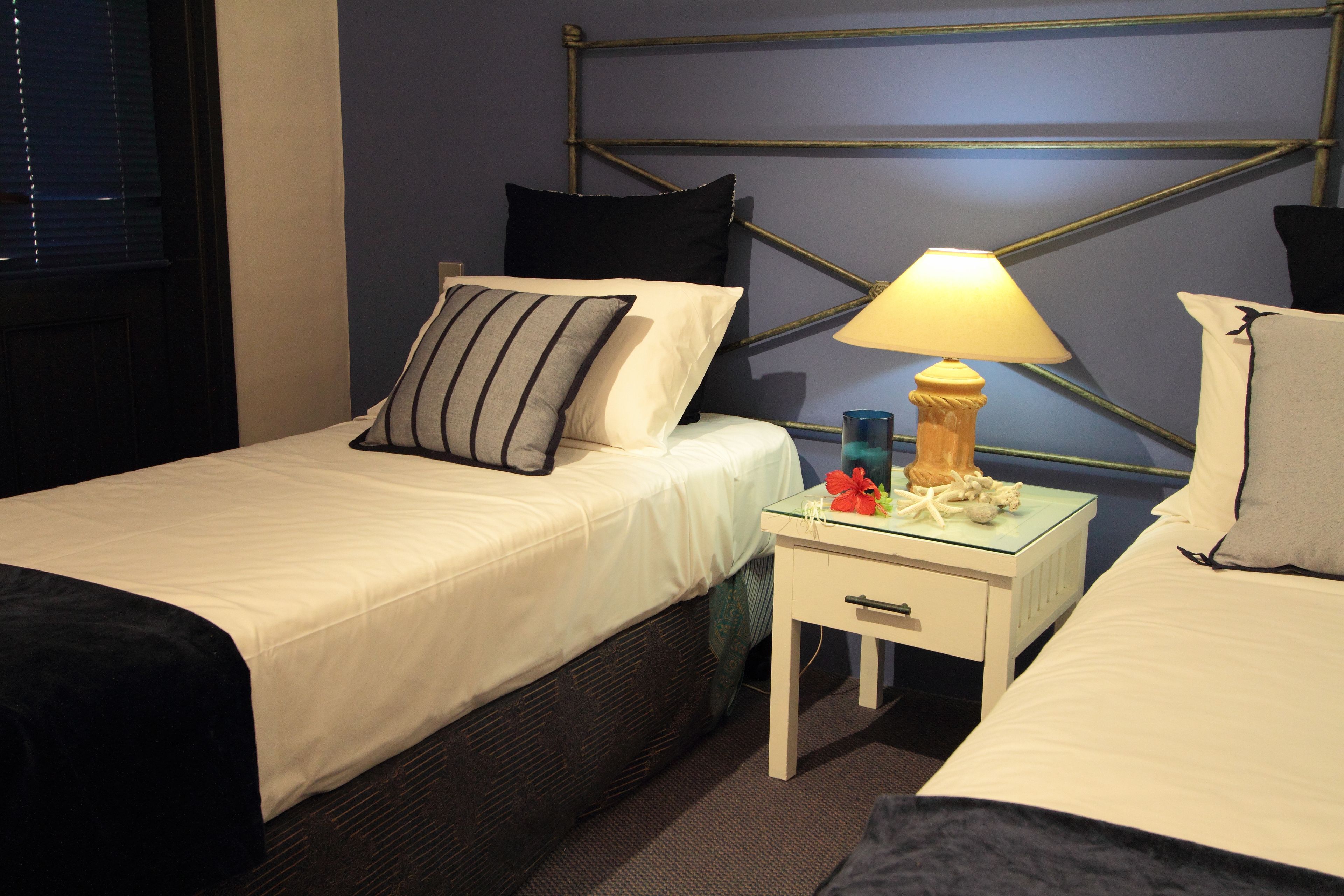 Une chambre d’hôtel avec deux lits, une table de chevet avec une lampe et un panneau décoratif au mur.