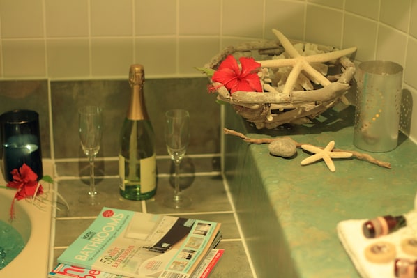 A bathroom counter with a magazine, a bottle of champagne, and a decorative starfish and flower arrangement.