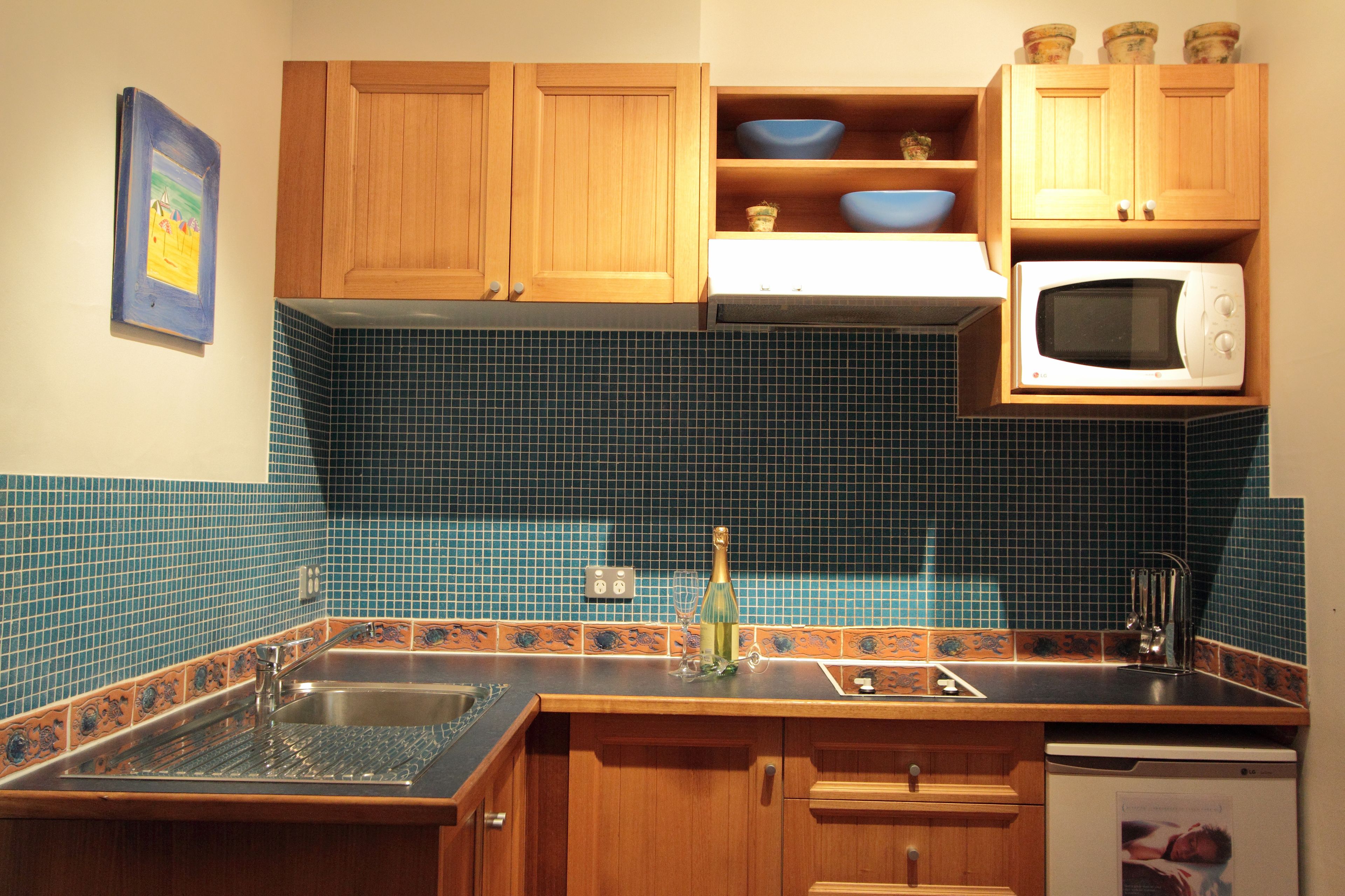 A kitchen with wooden cabinets, a microwave, a sink, and a tiled backsplash.